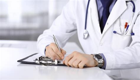 Premium Photo Unknown Male Doctor Sitting And Working With Clipboard